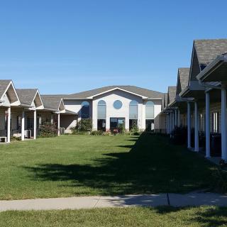 A sunny view of residential buildings with a green lawn and a clear blue sky.