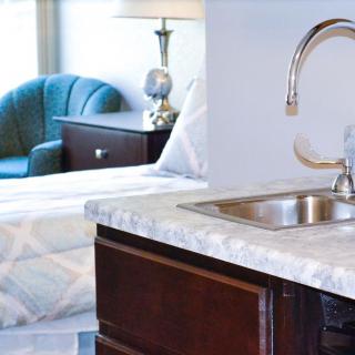 Modern kitchen area with a sleek countertop and shiny faucet, adjacent to a cozy living space.