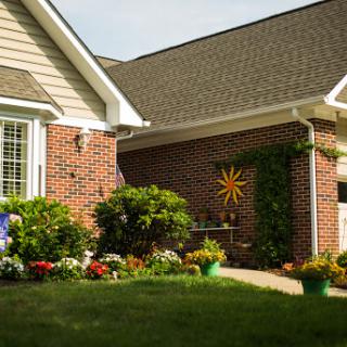 A charming house front with vibrant flowers and a sunny decoration, showcasing beautiful landscaping.