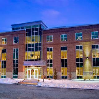 A modern architectural building illuminated at night with snow surrounding the entrance.