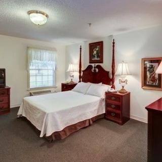 A traditional bedroom with a wooden bed frame, matching furniture, and elegant decor.