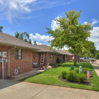A suburban brick house with a well-maintained lawn and driveway on a sunny day.
