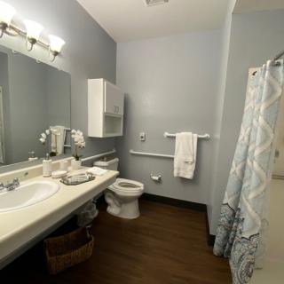 A neatly organized bathroom featuring a sink, toilet, and shower area.