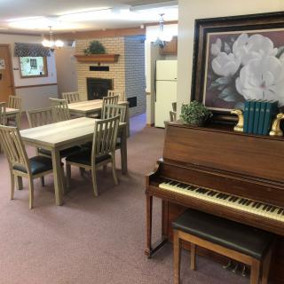 A cozy living space featuring a piano, dining tables, and a fireplace.