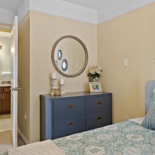 A cozy bedroom featuring a dresser with decorative items and a round mirror on the wall.