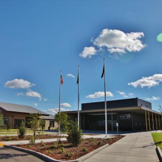 A modern school building with flags at the entrance under a partly cloudy sky.