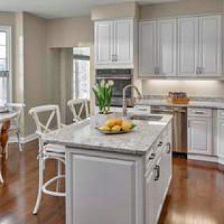 A modern kitchen with white cabinets, a central island, and wooden flooring.