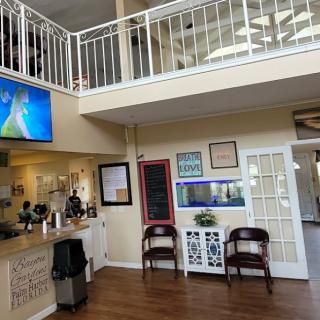 A view of a welcoming lobby with a reception desk, seating area, and a television mounted on the wall.