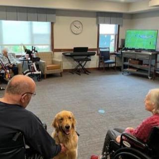 A therapy dog interacts with residents in a care home's community room.