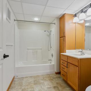 A modern bathroom featuring a shower, vanity cabinets, and contemporary lighting.