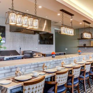 A modern restaurant interior featuring bar seating, elegant lighting, and a sleek countertop.