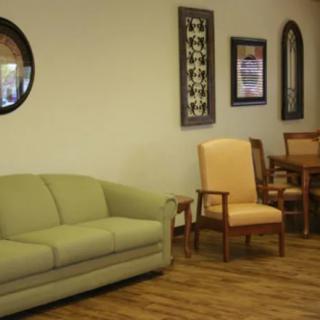 A waiting room with a sofa, chairs, and wall decorations.
