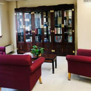 A cozy office waiting room with red armchairs, a coffee table, and a bookshelf.