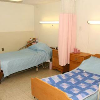 A hospital room with two beds and a privacy curtain.