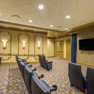 A small indoor theater room with rows of seating and a wall-mounted screen.