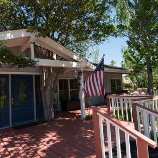 A quaint house with a blue door and an American flag on a sunny day.