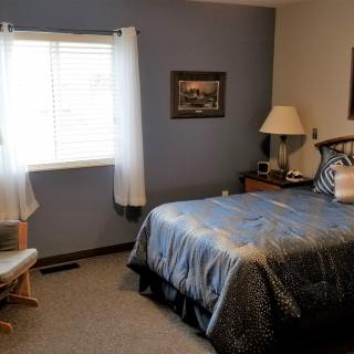 A cozy bedroom with a comfortable bed, side table, and window letting in natural light.