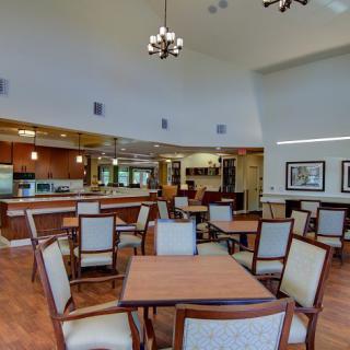 A spacious and elegantly designed dining area with wooden tables and upholstered chairs.