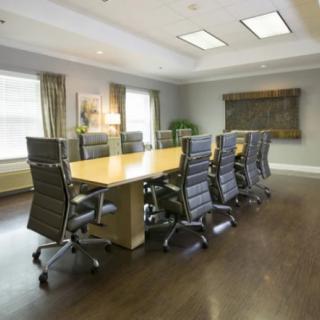 A modern conference room with a long meeting table and executive chairs.