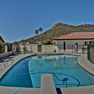 A serene outdoor swimming pool with a view of mountains and palm trees under a clear blue sky.