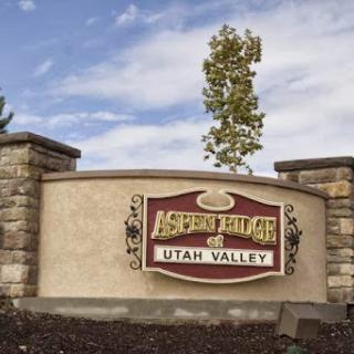 Welcome sign for Aspen Village in Utah Valley, showcasing natural elements and community identity.
