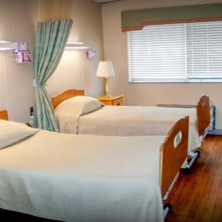 A clean and orderly hospital room with two beds and a window allowing natural light.