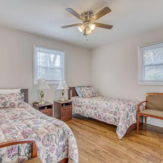A cozy bedroom featuring two beds with floral bedding and a ceiling fan.