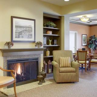 A cozy living room with a fireplace, armchair, and decorative shelves.