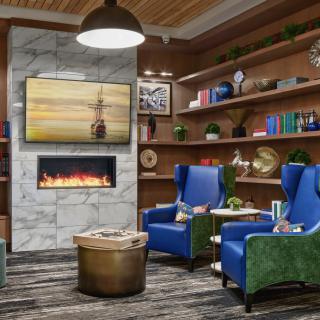 A cozy living room with modern design elements, featuring a fireplace, blue armchairs, and bookshelves.