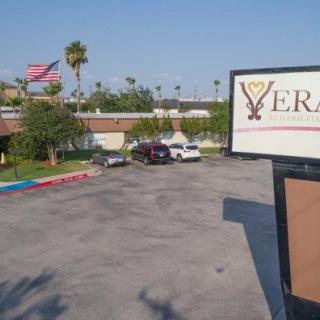 A view of a parking lot with a sign and several parked cars under a clear blue sky.