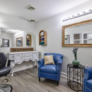 A stylishly decorated salon interior featuring blue chairs, a large mirror, and elegant lighting.