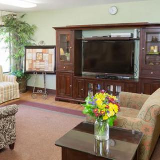 A cozy living room with a large television, elegant furniture, and a vase of colorful flowers on the coffee table.