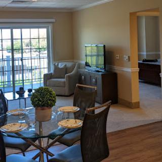 A bright and modern living space featuring a dining table, comfortable seating, and large windows that bring in natural light.