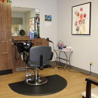 A cozy salon interior featuring a barber chair and mirror, surrounded by hair products and decor.