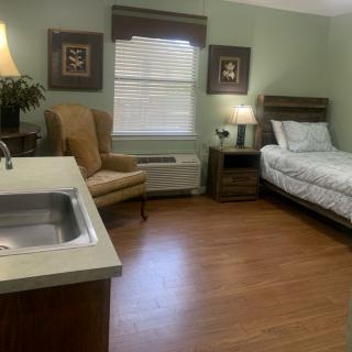 A cozy bedroom with a bed, chair, and warm lighting.