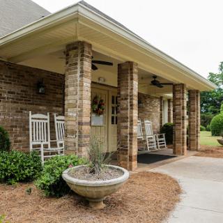 A welcoming entrance featuring a charming porch with rocking chairs and beautifully landscaped surroundings.