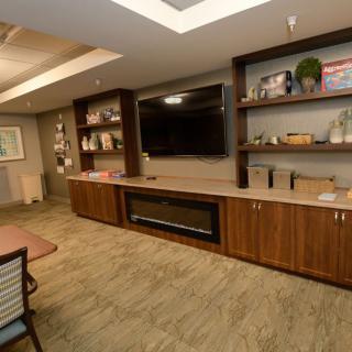 A modern living room with a large television, built-in shelves, and a fireplace.