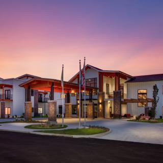 A modern building with flags at the entrance during sunset.