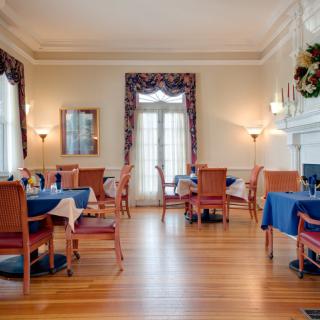 Elegant dining room with neatly arranged tables and chairs, featuring large windows and tasteful decor.