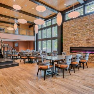 Modern restaurant interior with large windows, stylish furniture, and a cozy fireplace.