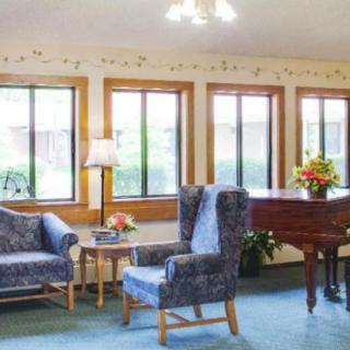 A cozy living room with seating area and a piano by the windows.