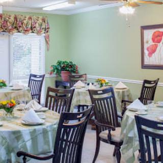 A beautifully arranged dining room with tables set for a meal, featuring green walls and floral decorations.
