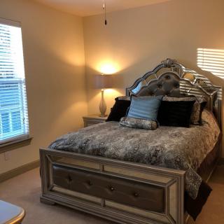 A cozy bedroom with a neatly made bed and ambient lighting.