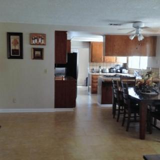 An open-plan kitchen and dining area with wooden cabinets and a dining table.