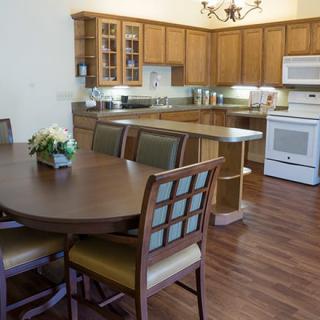 A cozy kitchen with wooden cabinets and a dining area featuring a round table with chairs.
