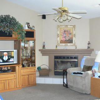 A cozy living room featuring a sofa, armchair, fireplace, and television.