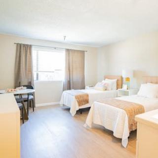A bright and minimalist bedroom featuring two twin beds and ample natural light.