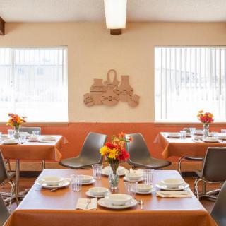 A cozy restaurant interior with tables set for dining, featuring floral centerpieces and decorative wall art.
