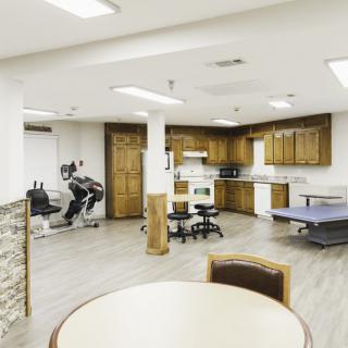 A rehabilitation therapy room equipped with exercise machines and a kitchenette.