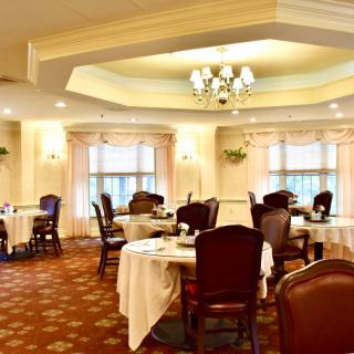 An elegant dining room with neatly arranged tables and chairs, featuring a chandelier and soft lighting.